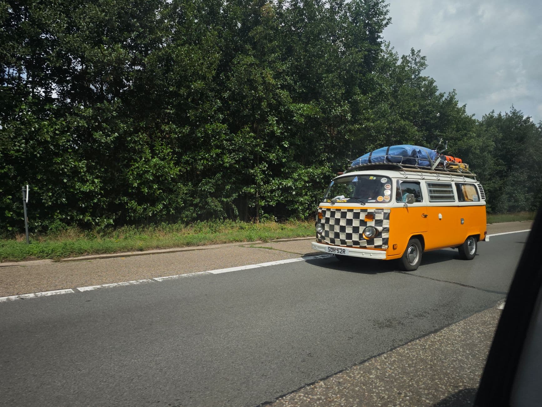 Retro yellow VW camper van driving through lush German countryside.