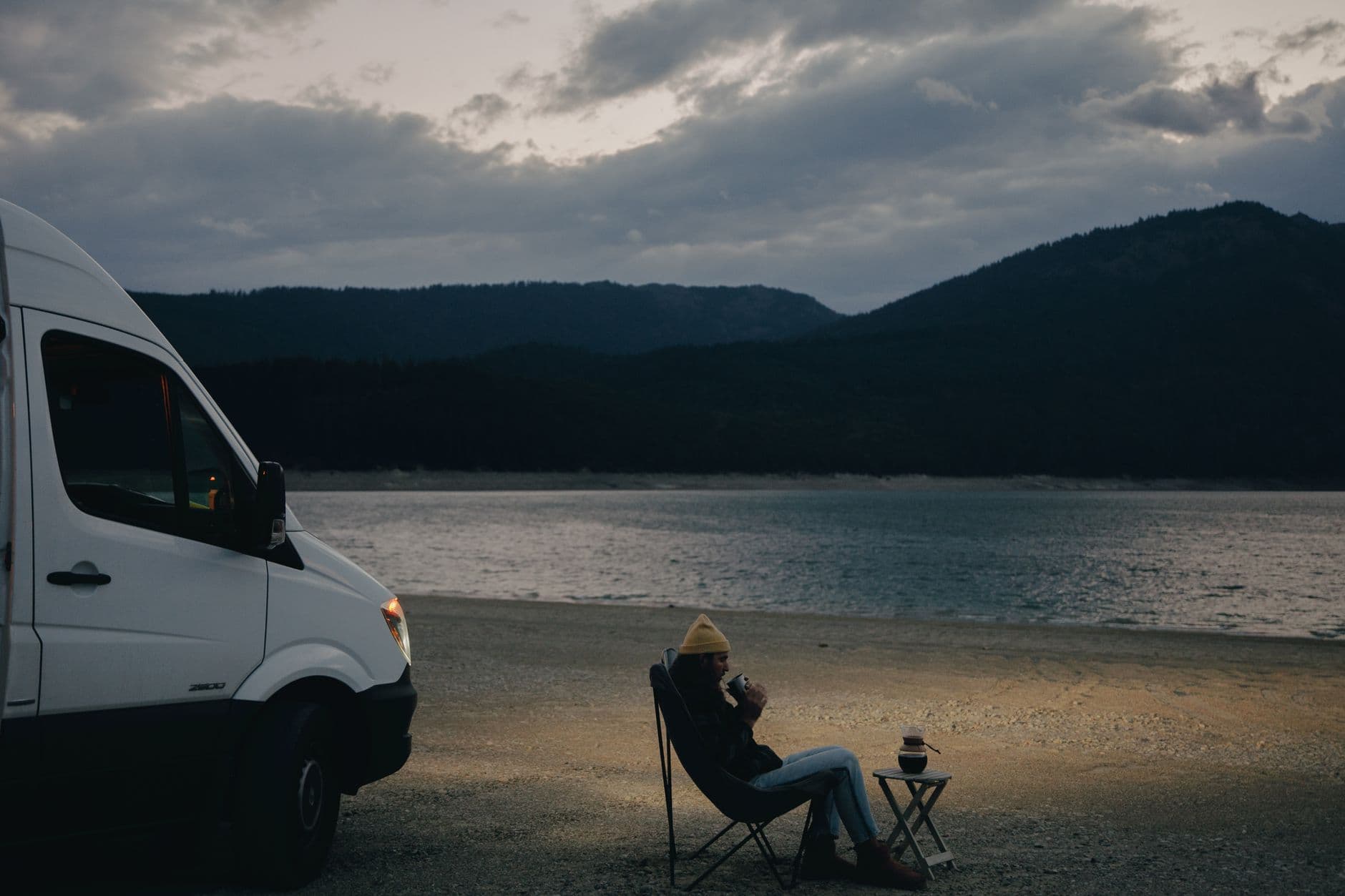 Un camping-car au bord d'un lac au coucher du soleil.