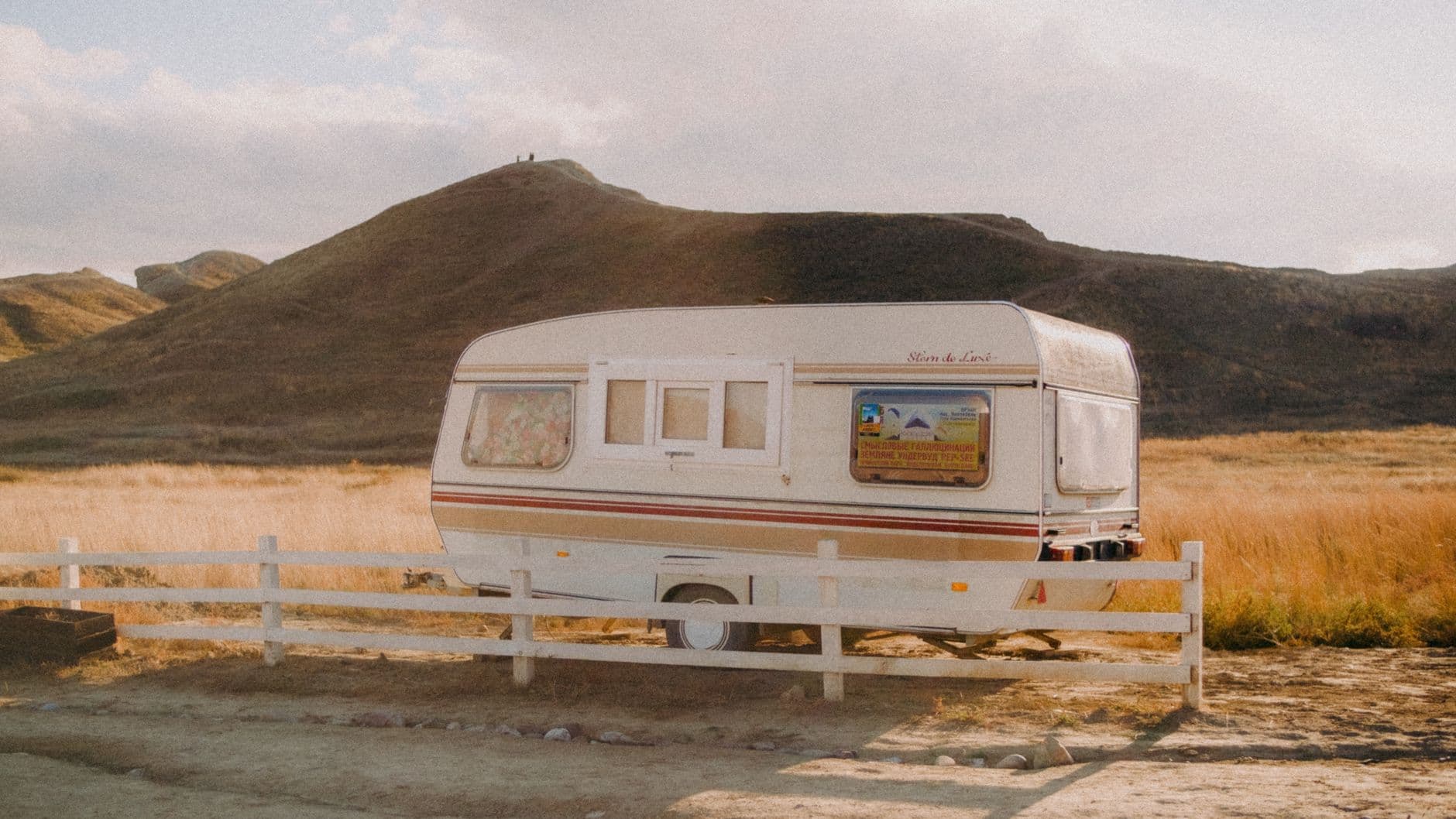 Une caravane installée dans une prairie au lever du jour.